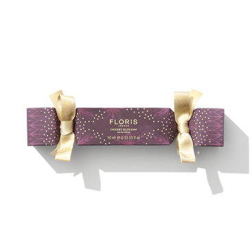 A purple and gold holiday cracker labeled "Cherry Blossom Holiday Cracker" from Floris London EU evokes the charm of a British tradition during the festive holiday season.
