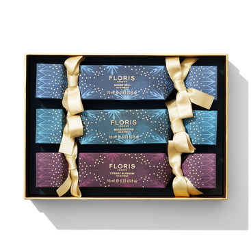 Introducing the Holiday Cracker Collection by Floris London EU: a set of four beautifully packaged fragrance bottles, each adorned with gold ribbons. Perfect for celebrations, this gift box includes enchanting scents of Honey Oud, Mulberry Fig, and Cherry Blossom.