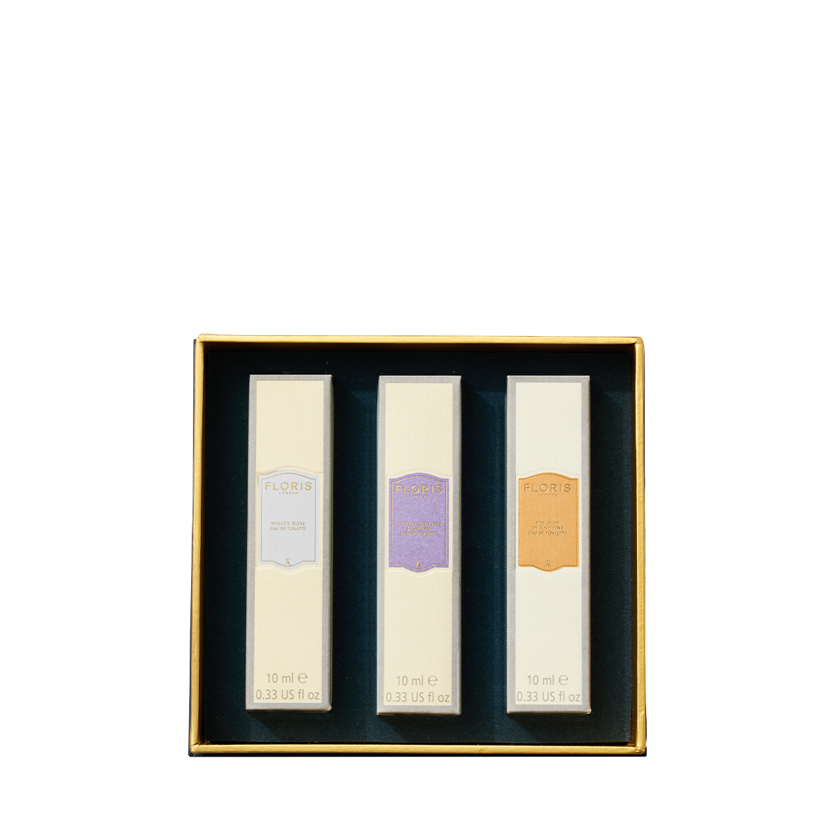 A gold-edged box holds three 10ml bottles of Floris London EU’s Perfumer's Trilogy: For Her, each in a white package with colorful labels.