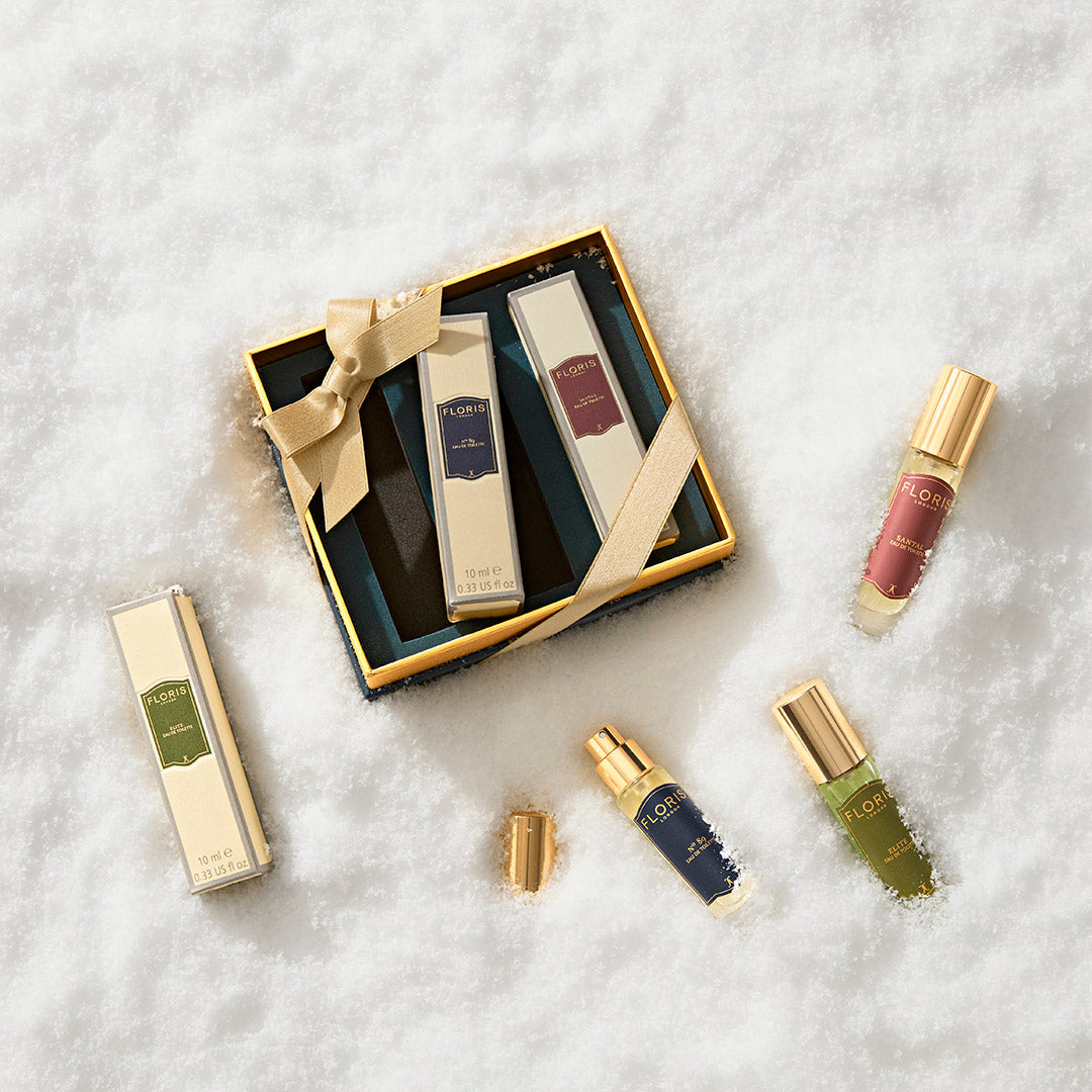Perfumer's Trilogy: For Him by Floris London—gold-capped gift box of British men’s fragrances on white snow, perfect for the festive season.