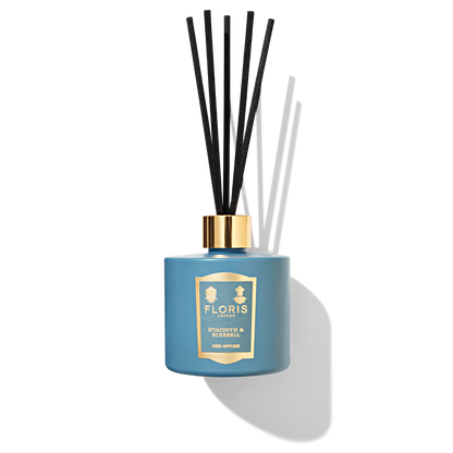 Sky blue reed diffuser bottle with 5 black reeds in a blue and gold label reading ' hyacinth and bluebell reed diffuser'.