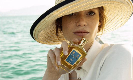 A model holding a glass perfume bottle by her face