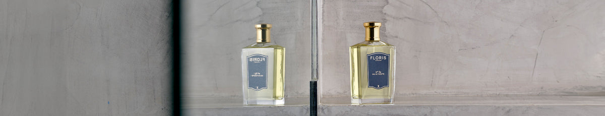 A bottle of perfume and a wooden container on a rustic wooden bench beside a green plant.