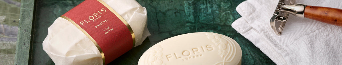 Four floral-themed skincare products next to a light blue radio and decorative lamp on a patterned background.