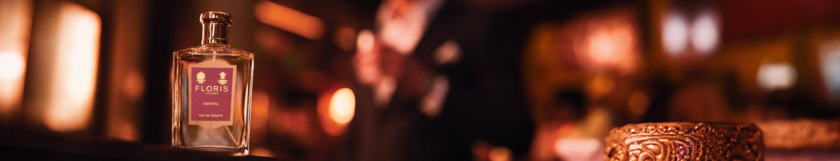 A Floris perfume bottle on a dark surface with a blurred, warm background.