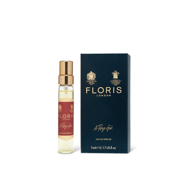 A 5ml perfume bottle labeled "A Rose For..." features a red label and gold cap, positioned next to a dark blue box marked with the brand name "Floris London." This bottle contains an exquisite oud-infused eau de parfum.