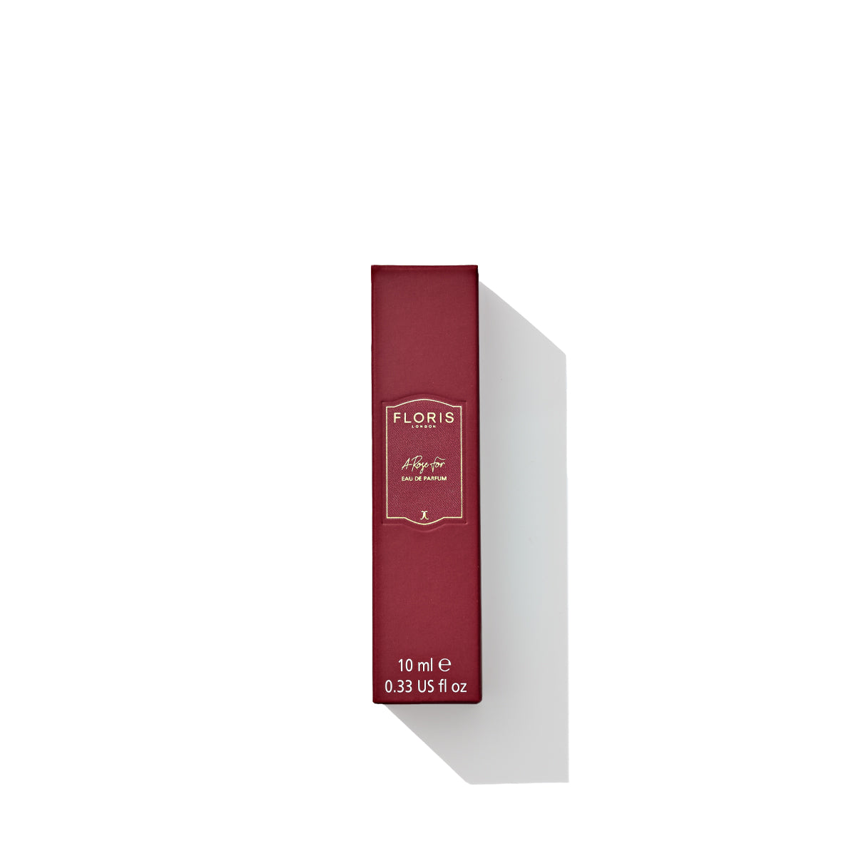 A red box of Floris London’s "A Rose For..." Eau de Parfum with gold lettering, stating it is 10 ml (0.33 US fl oz). The elegant packaging hints at an enticing fragrance blend with oriental rose and woody notes. The box stands poised with a shadow on a white background.