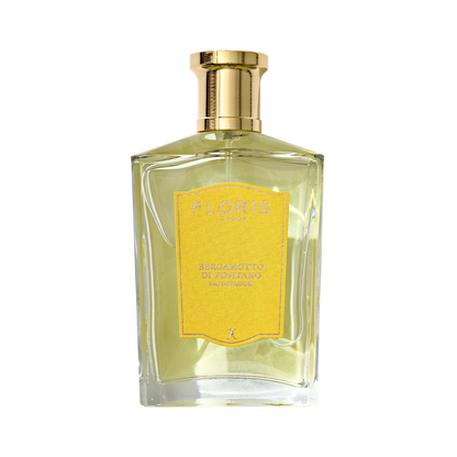 A clear glass bottle of Floris London Bergamotto di Positano Eau de Parfum, featuring a gold cap, yellow label, and pale yellow fragrance inside.