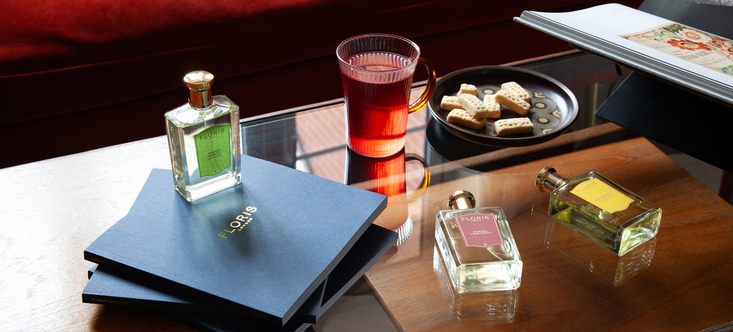 A coffee table adorned with a pile of Floris London 2024/25 catalogues, Jermyn Street, Santal and Bergamotto di Positano fragrances, a warm tea and a plate of shortbread biscuits.  