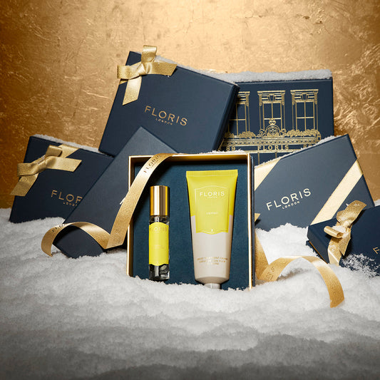 Floris London EU's Cefiro Hero and Cefiro Duo gift set, with lotion and spray in yellow packaging, is boxed with gold ribbon amid navy boxes on snow.