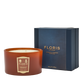 The Floris London EU Cinnamon & Tangerine Deluxe Three Wick Candle rests by its blue box, bringing cozy fragrance to a crisp white setting.