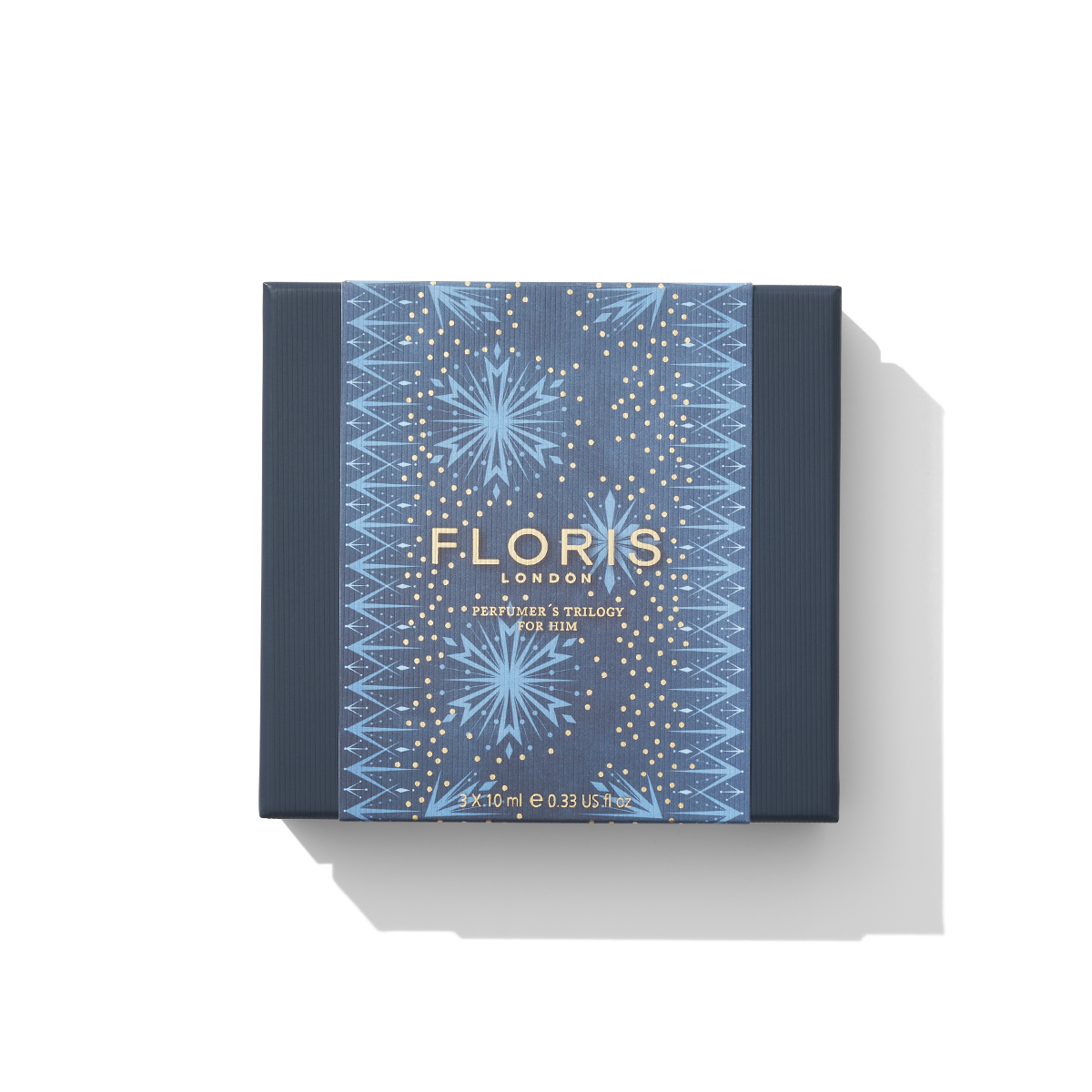 A rectangular product box labeled "Floris London EU" in gold text on a blue and gold geometric patterned background, with the subtitle "Perfumer's Trilogy: For Him," makes a perfect festive gift for those who appreciate British men's fragrances.