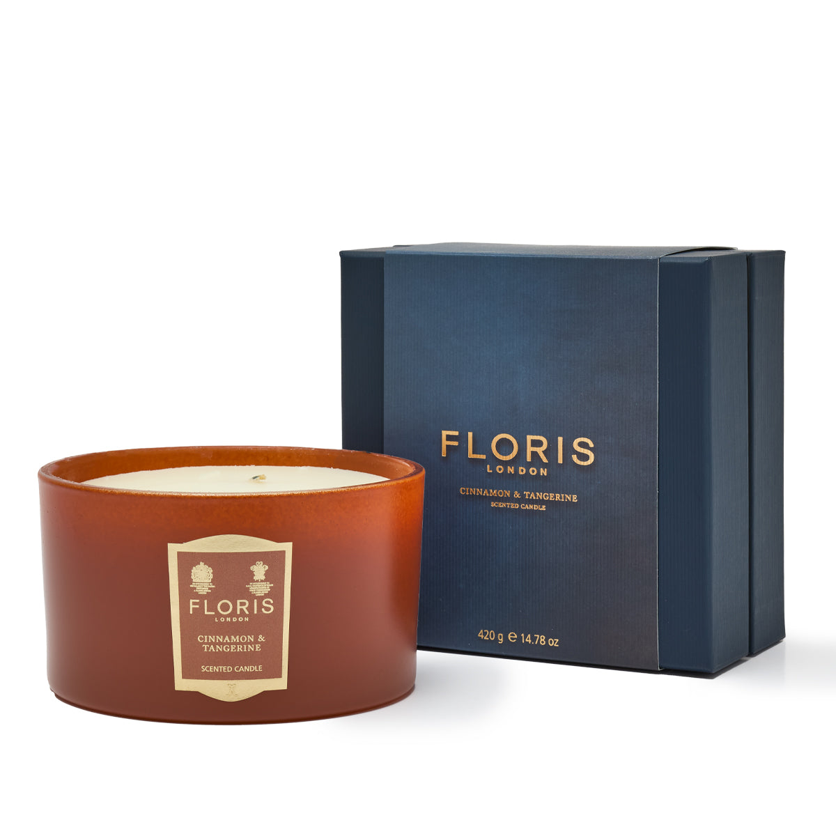 A Floris London EU Cinnamon & Tangerine Deluxe Three Wick Candle is showcased beside its elegant dark blue packaging box. Weighing in at 420 grams (14.78 ounces), this exquisite candle combines the warm spice of cinnamon with the invigorating zest of tangerine.
