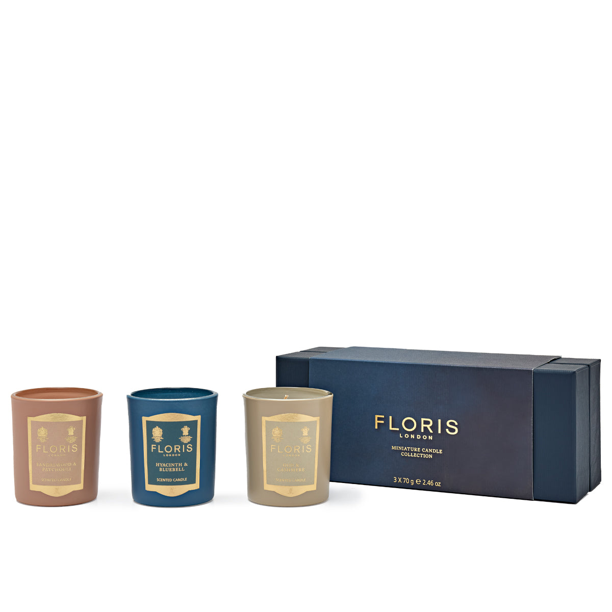 Displayed next to a matching navy blue box are three beautifully scented candles in brown, blue, and cream jars labeled "Floris." The box reads, "Floris London EU Miniature Candle Collection.