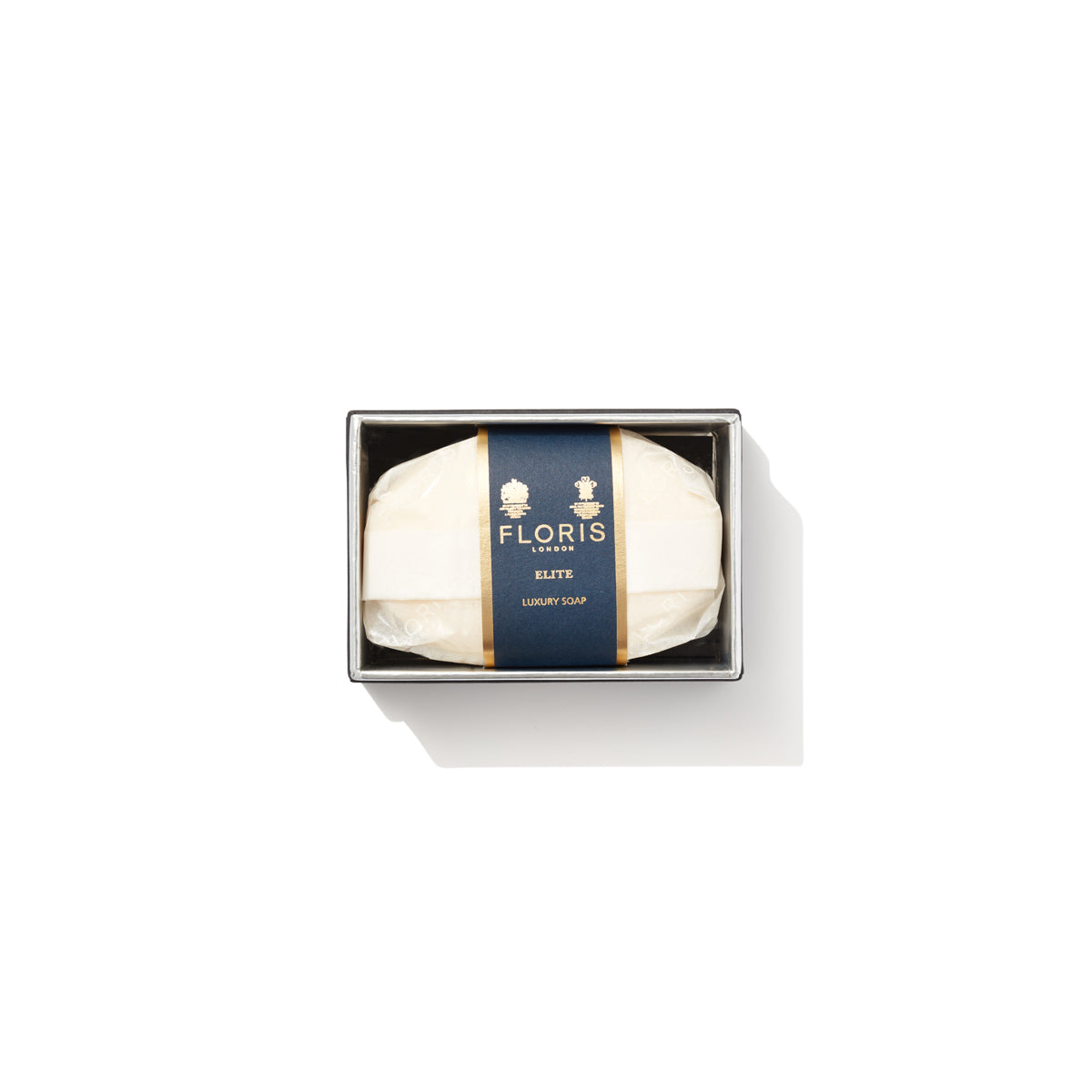 A bar of Floris London EU Elite Soap with a woody scent, wrapped in white paper with a dark blue and gold label, sits boxed on a white background.