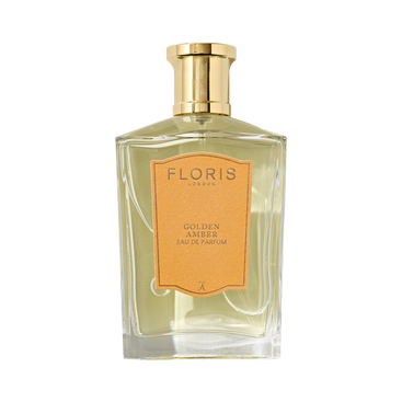 A clear glass bottle of Floris London’s Golden Amber – Eau de Parfum, a floral scent, features a gold cap and peach label on the front.