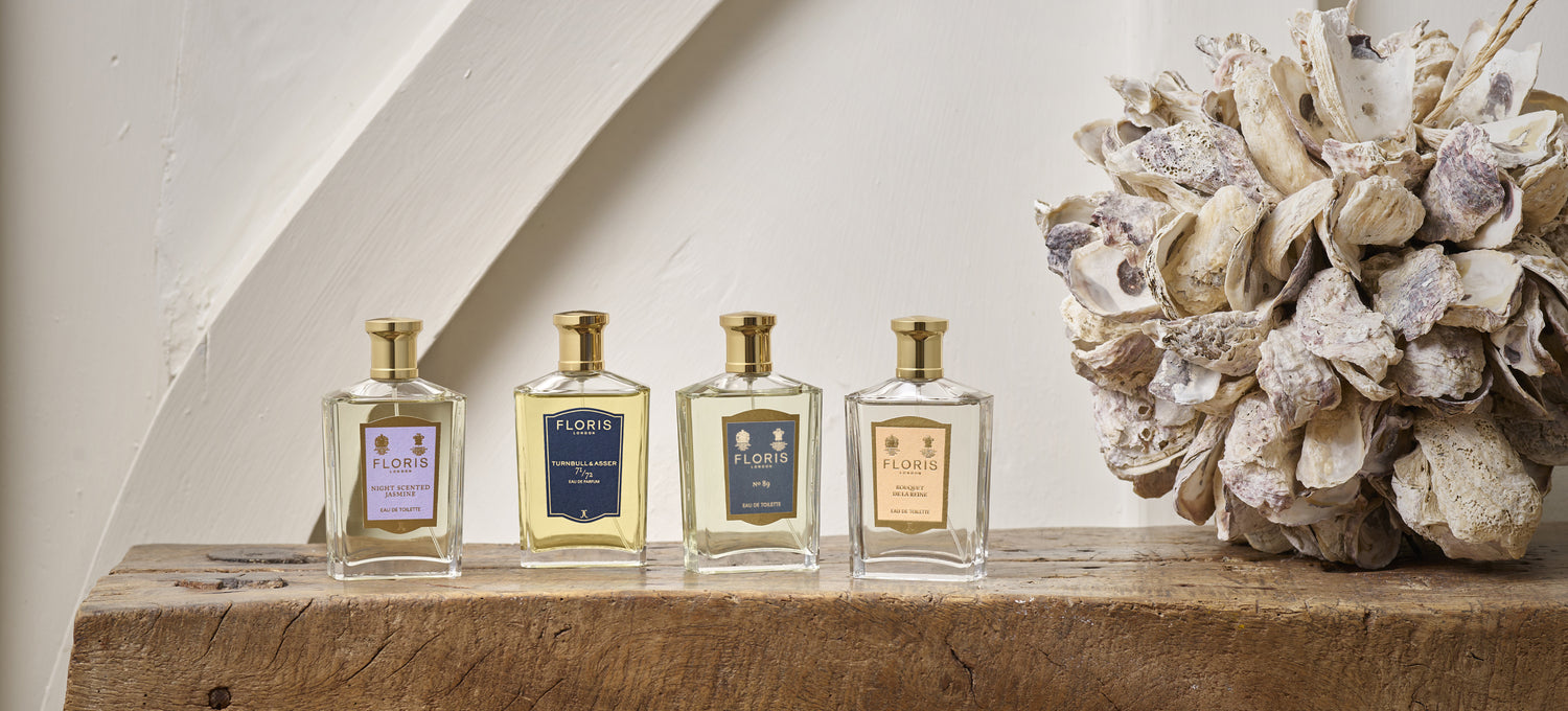 A Collection of Floris London Fragrances Including Night Scented Jamsine, 71/72, No. 89 and Bouquet de la Reine, placed upon a wooden stool next to a ball of oyster shells. 