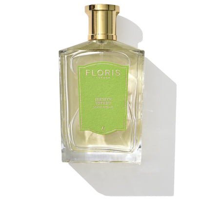 A bottle of Jermyn Street - Eau de Parfum from Floris London has a clear liquid and a gold cap with a green label, featuring notes of gin and vetiver.