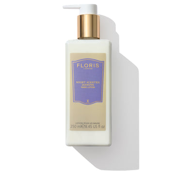 A bottle of Floris London EU Night Scented Jasmine Hand Lotion featuring a white pump, gold cap, and a purple label. The beige front label indicates that it is enriched with soothing sweet almond oil and vitamin E, making it nourishing for dry skin. A shadow is cast on the right side.