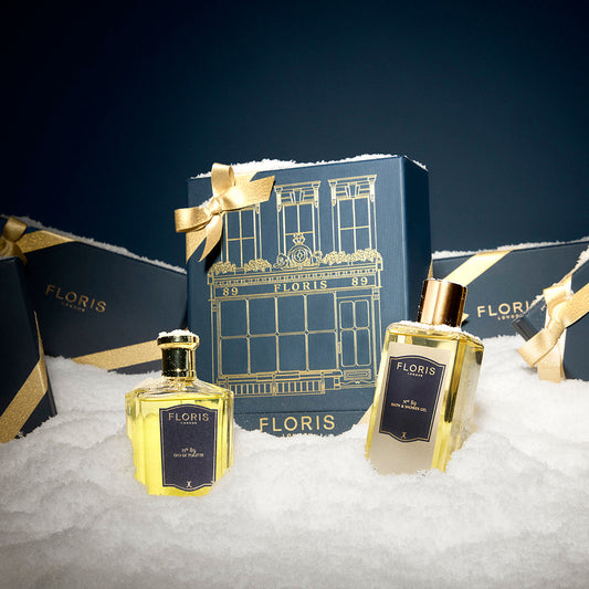 The Icon | No. 89 Duo by Floris London EU is displayed before blue and gold gift boxes, all arranged atop a bed of artificial snow.