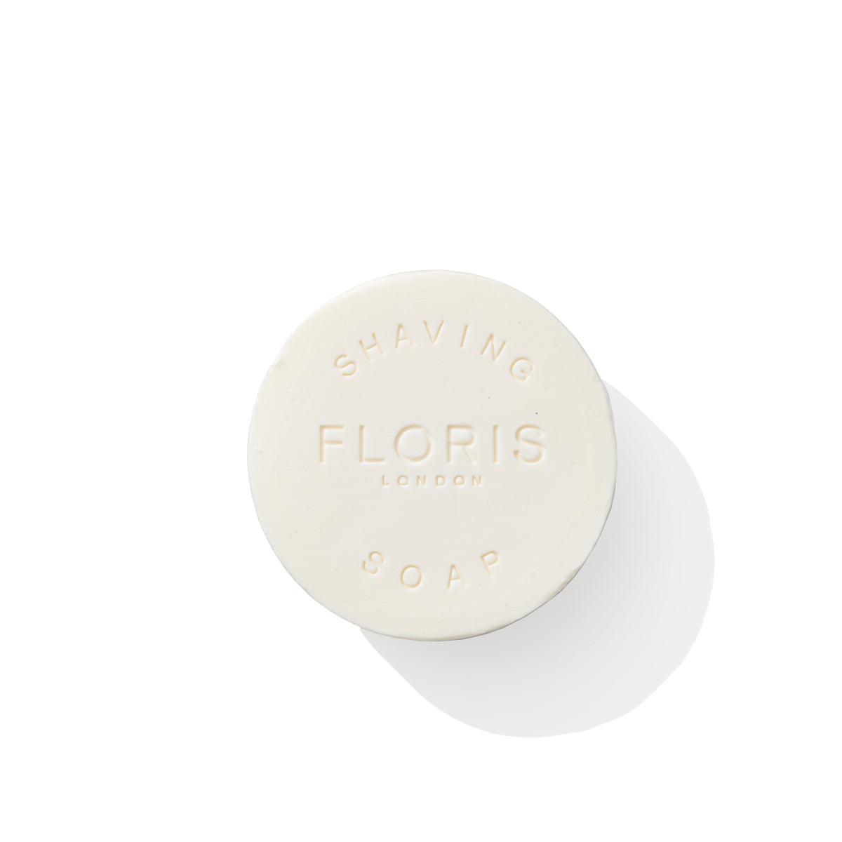 A white, round bar of No. 89 Shaving Soap Refill from Floris London, featuring embossed text on the surface. Infused with the warm essence of sandalwood, this product ensures a luxurious shaving experience. Photographed against a plain white background.