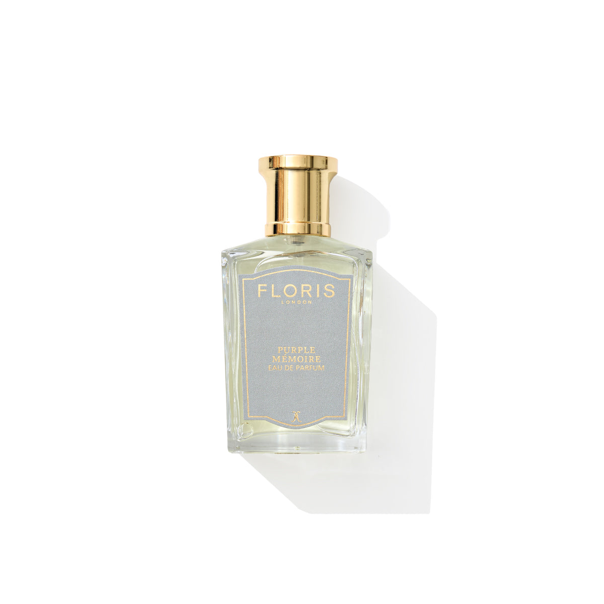 A bottle of Floris London Purple Mémoire Eau de Parfum exudes a delightful fragrance, capped in gold with a label of "Floris London" on a white background.