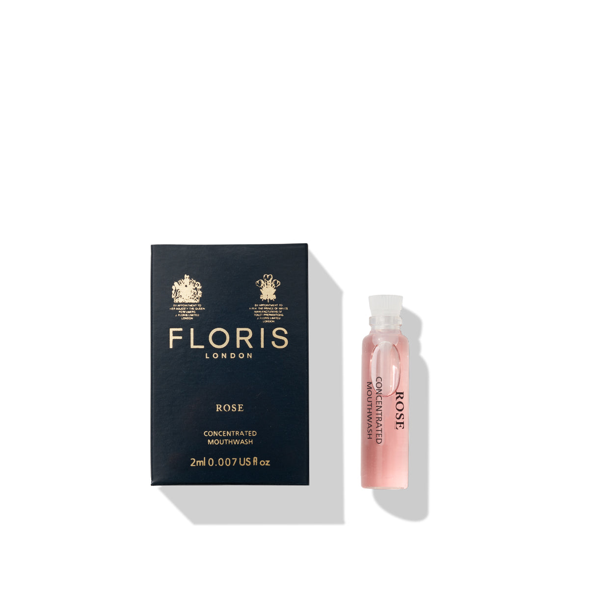 A 2ml sample bottle of Floris London Rose Mouthwash, featuring a subtle floral flavor, sits beside its dark blue box adorned with "FLORIS LONDON" in gold text and detailing.