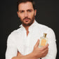 A man in a white button-up holds Sandalwood by Floris London EU, showcasing its rich sandalwood scent against a dark background as he faces the camera.