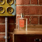 A bottle of Floris London Special No. 127 - Eau de Toilette, a citrus floral scent, sits on wood by a brick wall and vintage yellow electrical panel.