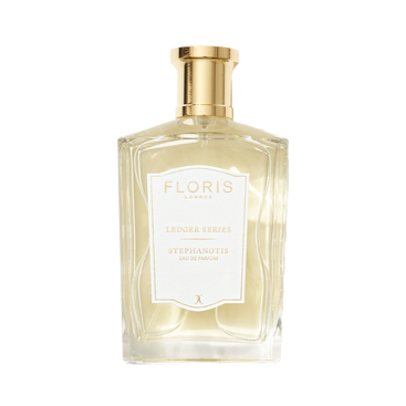 A clear glass bottle of Floris London EU Stephanotis perfume with a gold cap, white label, and light yellow floral fragrance inside.
