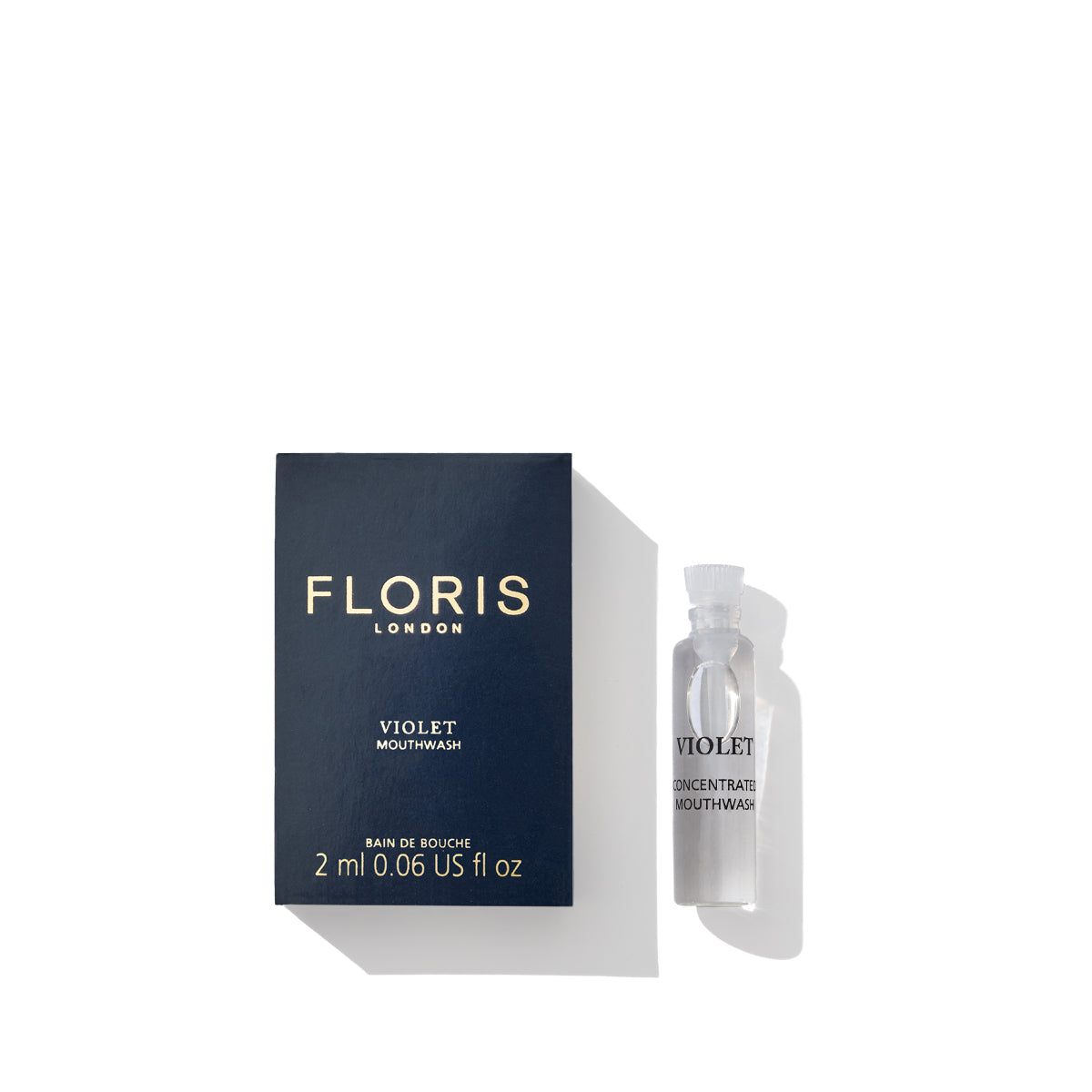 A box of Floris London's Violet Mouthwash and a small 2ml vial of the fluoride-free mouthwash concentrate are placed beside it on a white background, showcasing luxury dental hygiene.