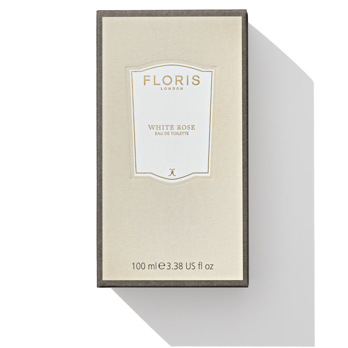 A rectangular box of Floris London's White Rose Eau de Toilette, 100 ml (3.38 US fl oz), featuring a beige label on a white background casting a shadow to the right, evokes the lush scent of velvet roses intertwined with warm amber notes.