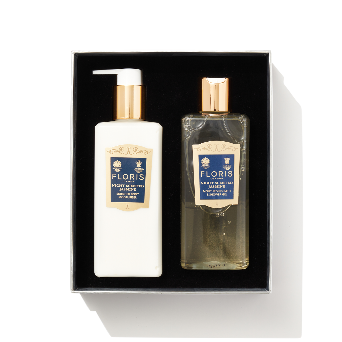 Two clear plastic pump bottles next to each other with navy and gold labels, inside a black gift box containing the Night Scented Jasmine Bath & Body Set.