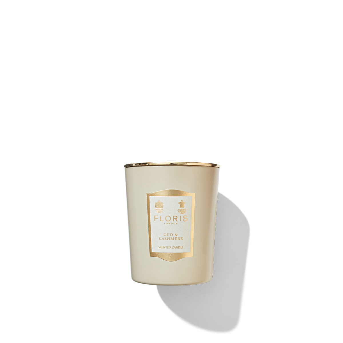 Oud & Cashmere Candle in a round beige matte glass jar, with a cream and gold label and shiny metal gold lid.