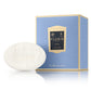 A white oval shaped soap pictured next to its light blue packaging box with gold and blue labelling.
